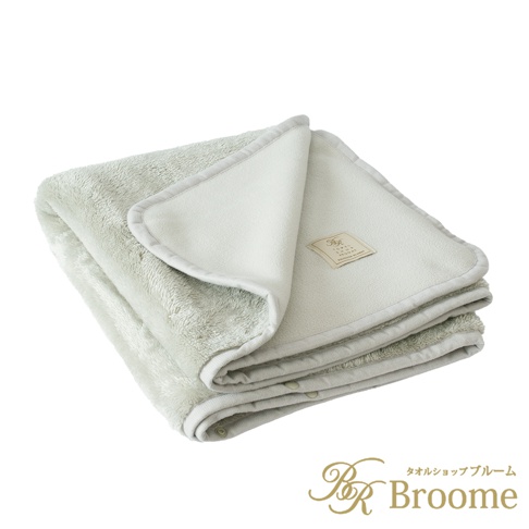 淺綠色法蘭絨保暖毯，兩面材質不同，一面為毛絨，一面為細緻的絨布，邊緣縫有淺灰色滾邊，毯子上縫有品牌標籤。