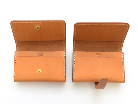 職人手作皮革經典名片收納夾，天然原色皮革，雙面展示，左側為開蓋式設計，附有黃銅按扣，內部有兩個卡槽；右側為翻蓋式設計，附有皮質綁帶，內部有兩個卡槽，邊緣皆以米白色縫線手工縫製。