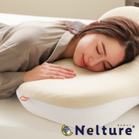 一位女性側臥在乳白色、帶有細緻紋路的 Q 彈棉花糖枕上，枕頭輪廓符合人體工學，邊緣飾有白色網眼材質，左側有橘色品牌標籤，右下角為「Nelture」品牌標誌。