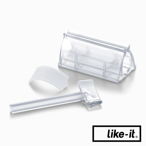 透明塑膠製成的三件式手動轉轉擠牙膏夾，包含一個彎曲的蓋子、一個帶有擠壓機構的長柄，以及一個用於固定牙膏管的底座。