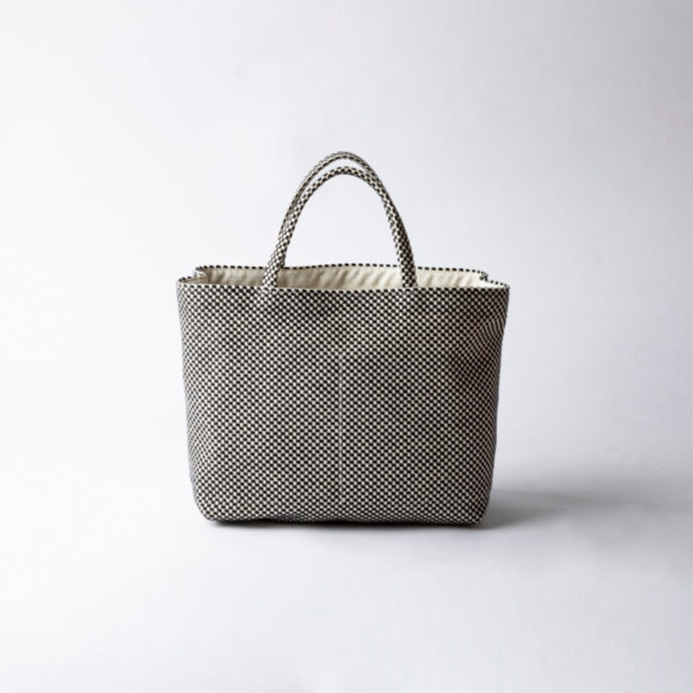 一個黑白格紋的刺子織多口袋托特包，有兩個提把，包身結構方正，內部為淺色布料。