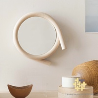一個圓形鏡子，被淺木色彎曲的木質框架環繞，框架形成不規則的螺旋狀，鏡子懸掛在米白色牆面上。
