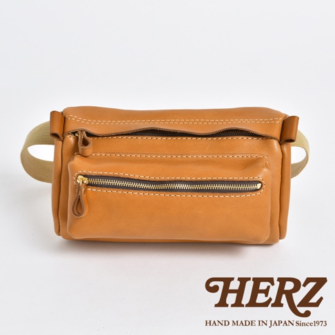 棕色皮革兩用腰掛斜背包，正面有兩個拉鍊口袋，附有卡其色織帶。