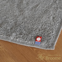 灰色長毛巾，材質柔軟，帶有今治品牌標誌，標誌為紅底白圓點，下方有藍色條紋。