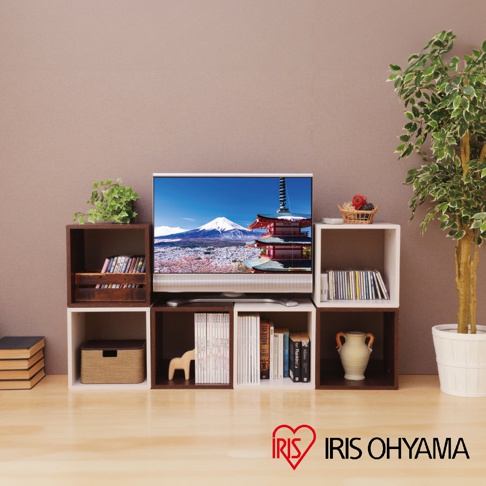 展示了圓角無門組合收納櫃，櫃體為木質，有深棕色和白色兩種顏色。櫃子上擺放著電視、書籍、裝飾品和植物，營造出居家生活氛圍。