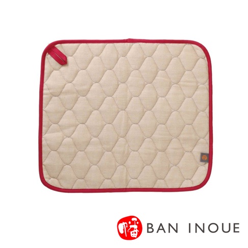 米色棉織吸水墊，菱形絎縫紋理，紅色滾邊，頂部有紅色掛繩，右下角有品牌標誌。