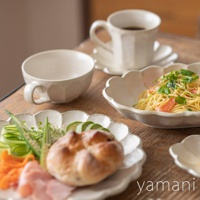 小兵美濃燒粉引湯杯碗，米白色陶瓷，帶有六魯紋理，搭配花瓣狀邊緣的盤子，盛有義大利麵、小麵包、生菜、小黃瓜、火腿和豆芽。