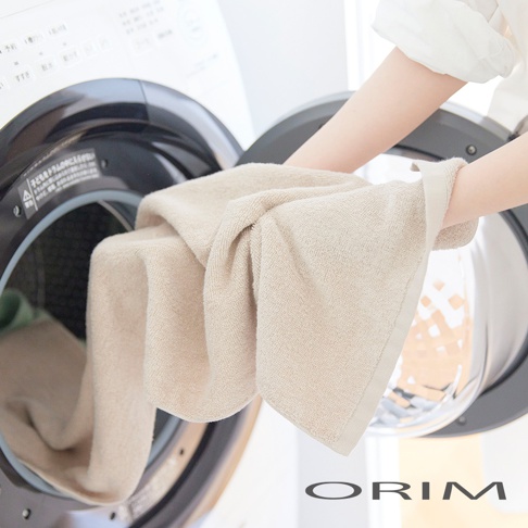 淺米色今治毛巾，柔軟的材質，被一隻手從洗衣機中取出。