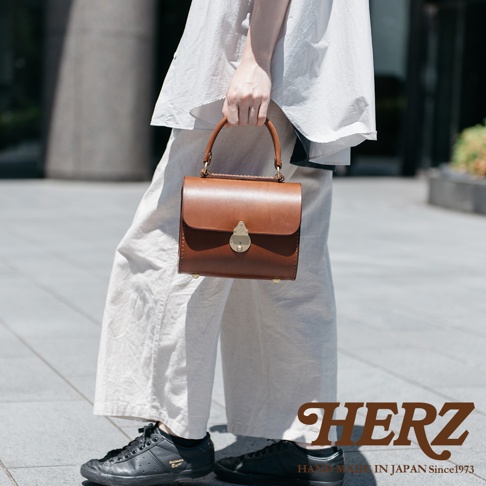 職人手作皮革復古杜勒斯手提包，採用咖啡色皮革，搭配金色鎖扣及腳釘，設計簡潔優雅，適合日常攜帶。