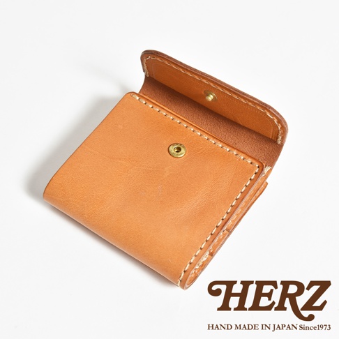 日本HERZ職人手作原色皮革短夾，採用質感厚實的Stare皮革製成，翻蓋處以金色金屬按扣開合，呈現簡約耐用的方正外型，右下方標註HERZ品牌商標與日本製造字樣，整體展現細膩的手縫工藝細節。