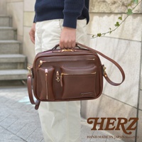 棕色皮革製成的手提斜背包，具有多個拉鍊口袋和可拆卸肩帶。