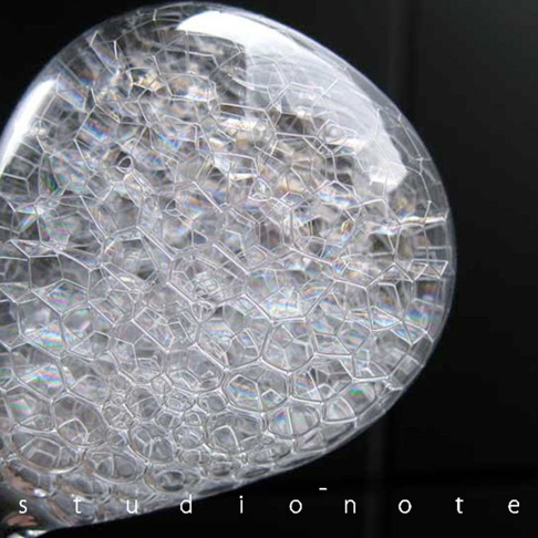透明玻璃製成的 awaglass mini 泡時計，內部充滿細密的白色泡沫，形成蜂窩狀結構，光線照射下呈現彩虹般的光澤。