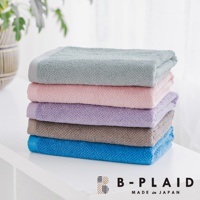 堆疊的五條浴巾，從上至下依序為淺灰綠、粉紅、淺紫、灰褐、藍色，皆呈現細緻的織紋，材質柔軟。