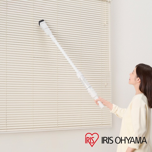 白色超輕量多合一手持無線吸塵器，長柄設計，前端裝有黑色刷頭，正被一名女性用於清潔米白色百葉窗。