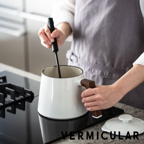 VERMICULAR 琺瑯鑄鐵壺，白色壺身搭配木質提把，壺內裝有黑色攪拌棒，放在電磁爐上，旁邊有一個白色壺蓋。