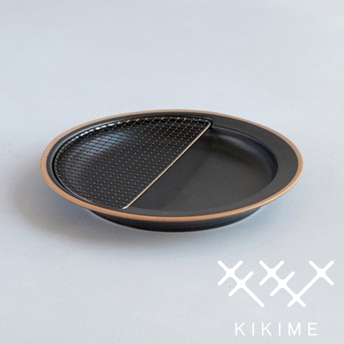 美濃燒質感的黑色橢圓形瀝油餐盤，盤面一半設有黑色金屬半月形濾網，盤緣帶有陶土原色。