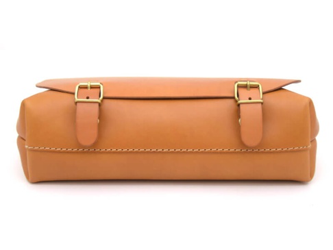 職人手作皮革雙扣三用後背包，採用淺棕色皮革製成，包身線條簡潔，配有兩個金色金屬釦帶，可扣合包蓋，底部有縫線裝飾。