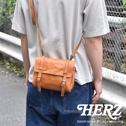 復古棕色皮革水洗加工郵差包，配有可調節肩帶和兩個磁扣皮帶。