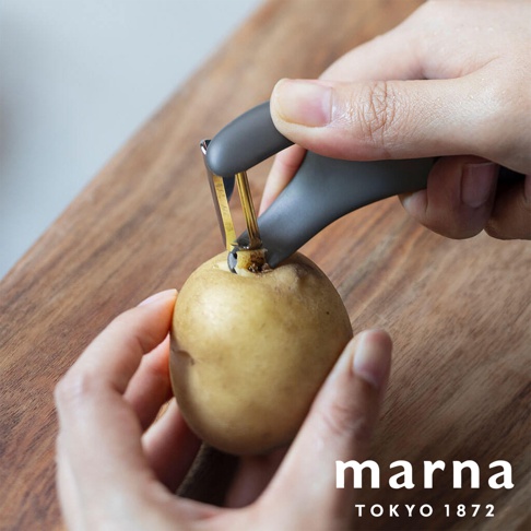 marna TOKYO 1872 品牌多功能削皮器，正用來削一顆馬鈴薯。