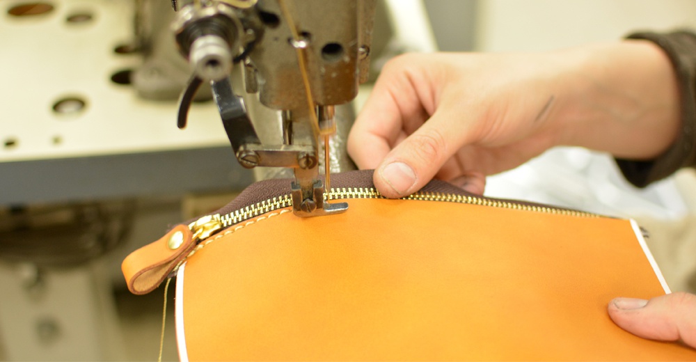 職人手作皮革後背包，橘棕色皮革，縫製咖啡色拉鍊與同色皮革提把，展現細膩工藝。