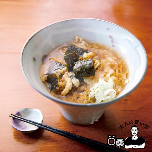 一碗熱騰騰的湯麵，內有海苔片、炸物和蔥花，搭配一雙筷子與醬油碟，置於木質桌面。