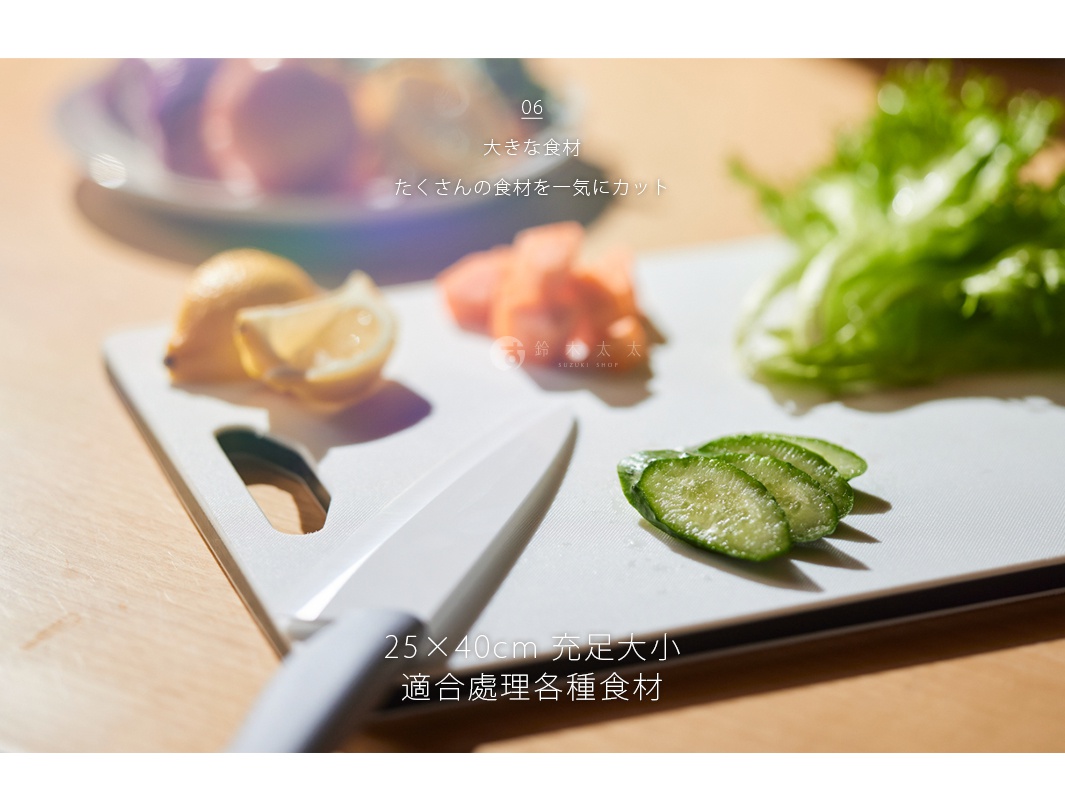 白色雙面抗菌耐熱砧板，上面擺放著切片的檸檬、胡蘿蔔、小黃瓜和生菜，旁邊還有一把白色菜刀。