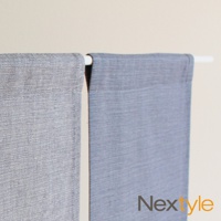 兩片淺灰藍色布簾，材質為織布，分別掛在白色桿子上。左側布簾紋理較細緻，右側布簾紋理較粗。