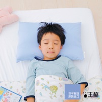 一個男孩側臥在床上，頭枕著淡藍色的「王様の小王子夢枕」。男孩穿著淺藍色長袖衣，蓋著一條印有獅子和花朵圖案的白色小被子。床單為白色，左側有一塊粉紅色的抱枕。