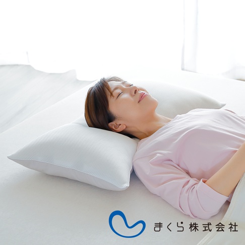 一名女子仰臥在白色床鋪上，頭枕著一個白色網狀表面的低枕。