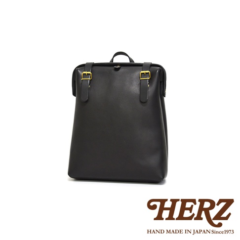 黑色皮革後背包，配有金色搭扣和提把，簡約設計，適合日常使用。