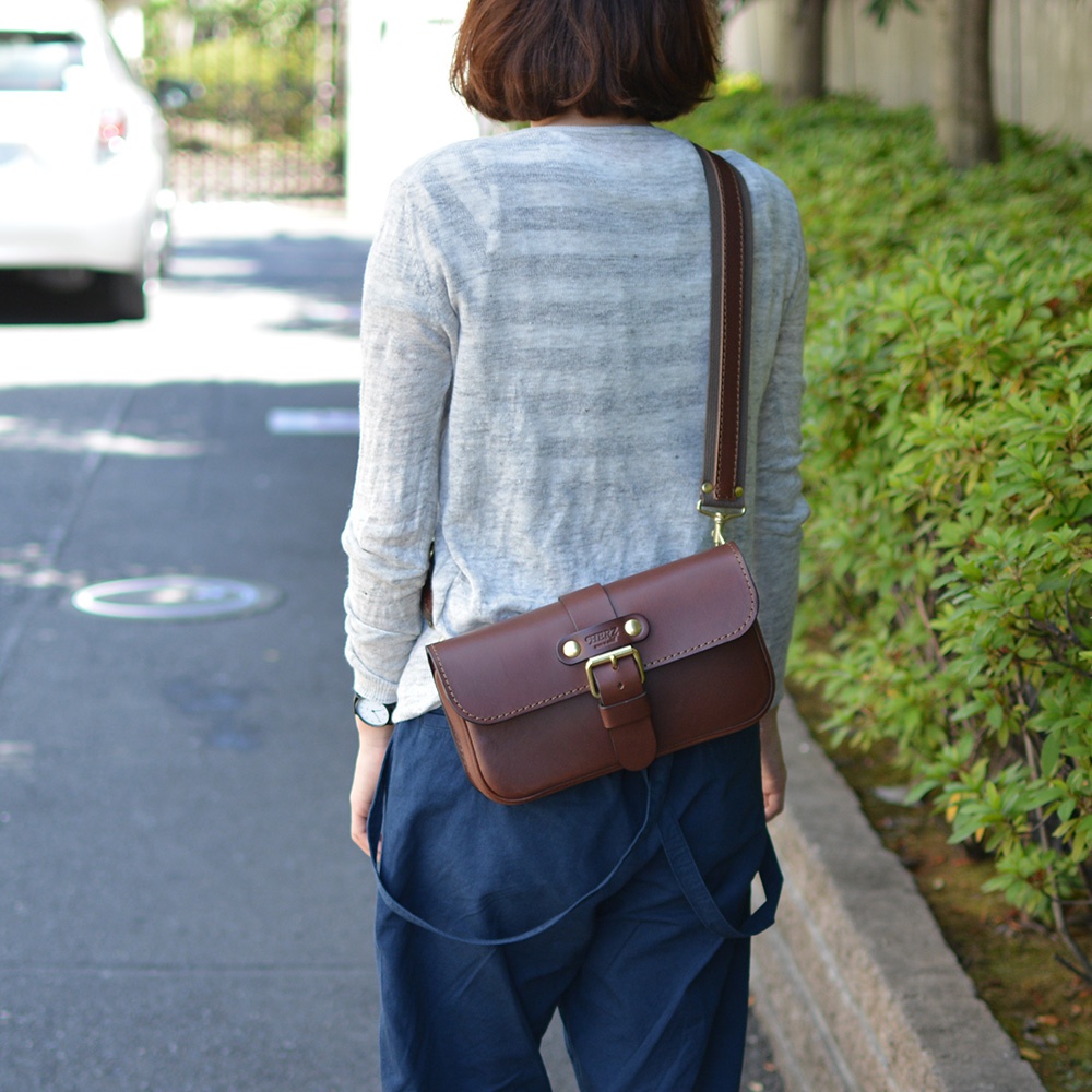 職人手作皮革單扣經典斜背包，深棕色，側邊斜背款式，具備金屬扣環和可調式肩帶。