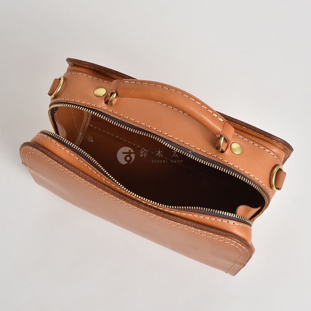 職人手作皮革兩用方形單肩包，淺棕色牛皮材質，帶有金色五金配件，拉鍊開合，可手提或肩背。