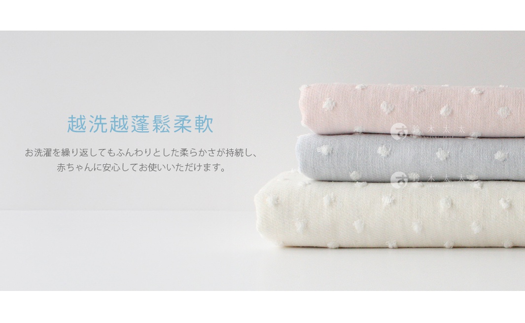 粉紅色、淺藍色和奶油色紗布織品堆疊，每塊織品都帶有凸起的小圓點圖案，材質看起來柔軟。