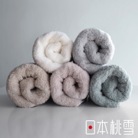 堆疊的柔軟毛巾，包括白色、米色、粉色、灰色和綠色，背景是灰色。