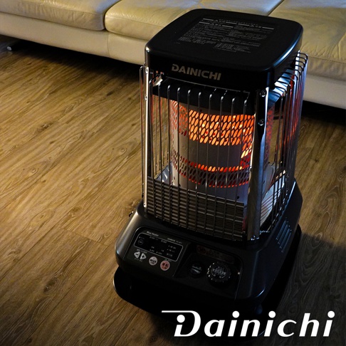 Dainichi 電子式煤油暖氣機，尊爵灰色，頂部黑色，帶有銀色金屬保護網，內部燃燒發出橘紅色火焰，底部黑色控制面板。