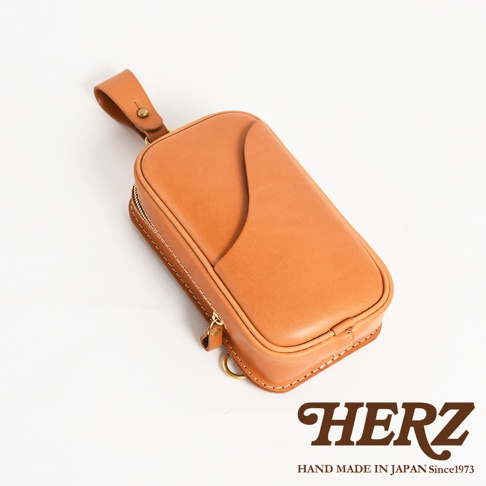 日本HERZ 職人手作皮革兩用直立型斜背包 F-103，淺棕色皮革材質，採用拉鍊開合，品牌標誌置於右下角，上方標示 HAND MADE IN JAPAN Since1973