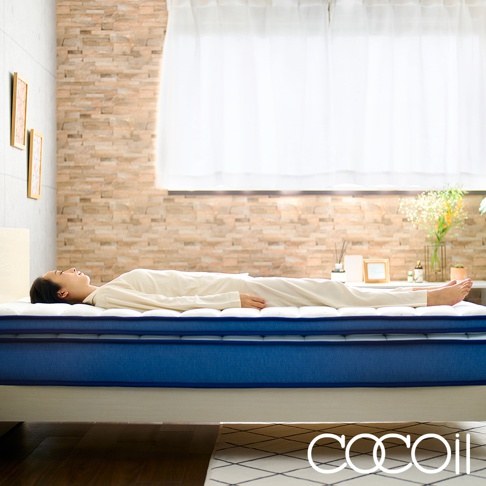 一位女性側臥於一張雙人床墊，床墊為白色表面搭配藍色邊條，具有獨立筒雙層結構。