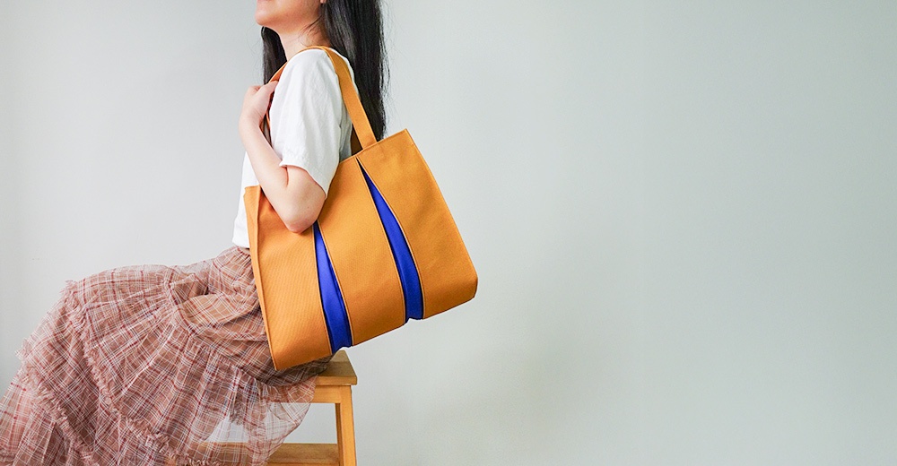 京都職人手作ougi棉帆布扇形托特包，主體為芥末黃色，搭配兩條鮮豔的藍色飾帶，設計簡約。