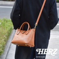 棕褐色皮革迷你托特包，配有可拆卸肩帶，包身設有頂部提把、金色金屬扣及四個底部防磨釘。