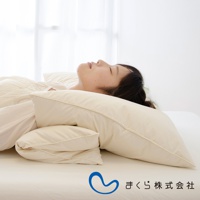 一組兩入的米白色羽絨枕，疊放在床上，一位女子側臥於枕上，畫面背景為明亮的窗簾。