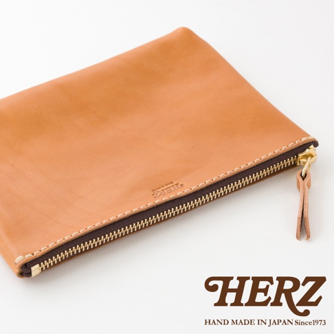 職人手作皮革長方形拉鍊收納包，淺棕色光滑皮革，搭配金色拉鍊與同色系皮革拉環，邊緣縫線為白色，包款上印有品牌壓紋。