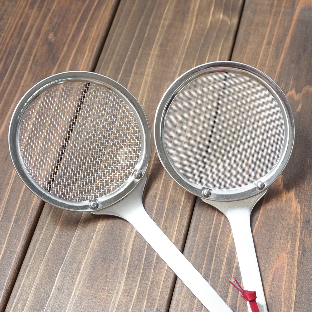 兩個不鏽鋼萬用撈泡勺，網篩細密，柄部連接處有鉚釘固定，置於木紋背景上。