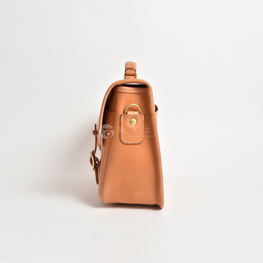 淺棕色皮革手提包，側面視角，包包上有兩個金屬扣環及一個提把，材質為皮革。