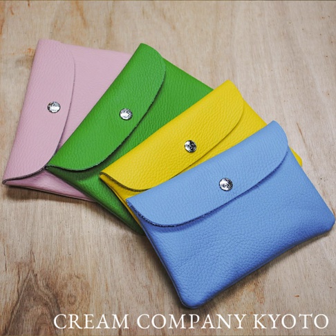 四款皮革收納包，分別為粉色、綠色、黃色和藍色，皆設有銀色按扣。