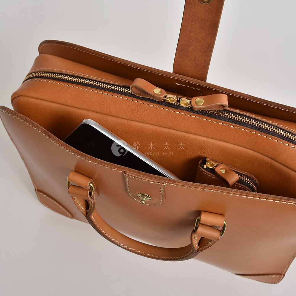 職人手作皮革三層收納兩用商務公事包 BW-4，展示的是溫潤的棕褐色全皮革材質，包身結構紮實，配有黃銅色拉鍊及細緻車縫線。包內可見一個手機及一個小零錢包。