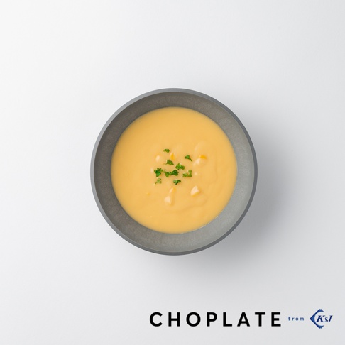 CHOPLATE BOWL沙拉碗，灰色外觀，內部裝有濃稠的黃色玉米濃湯，湯上點綴著少量玉米粒和切碎的綠色香草。