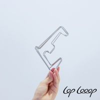 一隻手拿著一個銀色金屬製的伸縮式砧板架，其設計呈階梯狀，材質為不鏽鋼，背景為淺灰色。