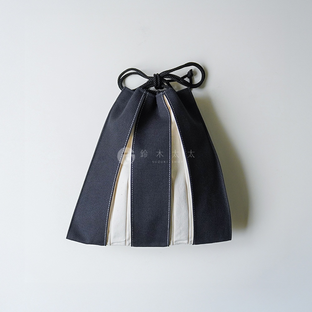 京都KOSHO帆布信玄袋，採用深灰色與米白色帆布拼接設計，呈現出簡約的幾何線條美感，上方配有黑色抽繩束口，整體外觀呈現梯形，風格優雅且富有日式手感。
