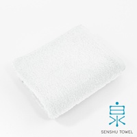 一條白色的長纖毛巾，材質蓬鬆柔軟，邊緣有精緻的包邊，右下角有藍色的「泉」字 Logo 和「SENSHU TOWEL」字樣。