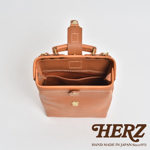 職人手作的棕色皮革迷你軟皮杜勒斯包，包身開口，內部有隔層，配有金色金屬扣和提把，展現自然皮革紋理。